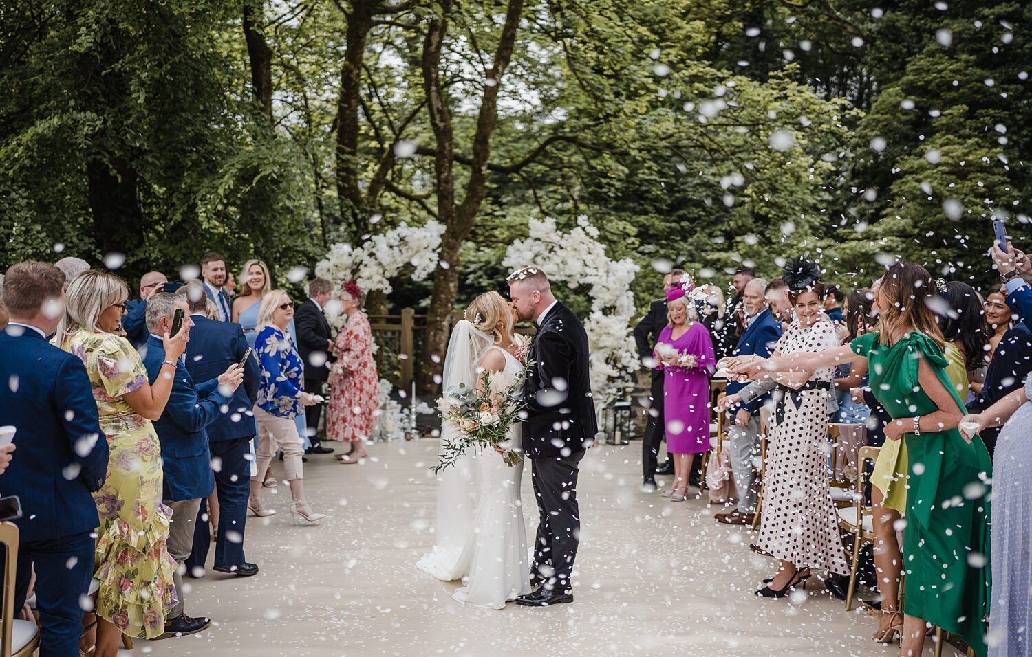 bride and groom kiss in confettit