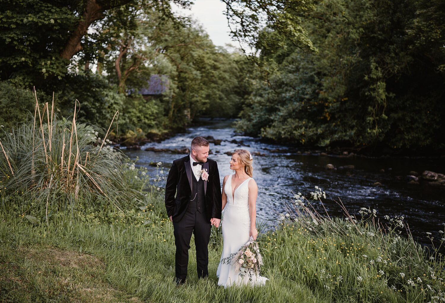 bride and groom holding hands down at the river